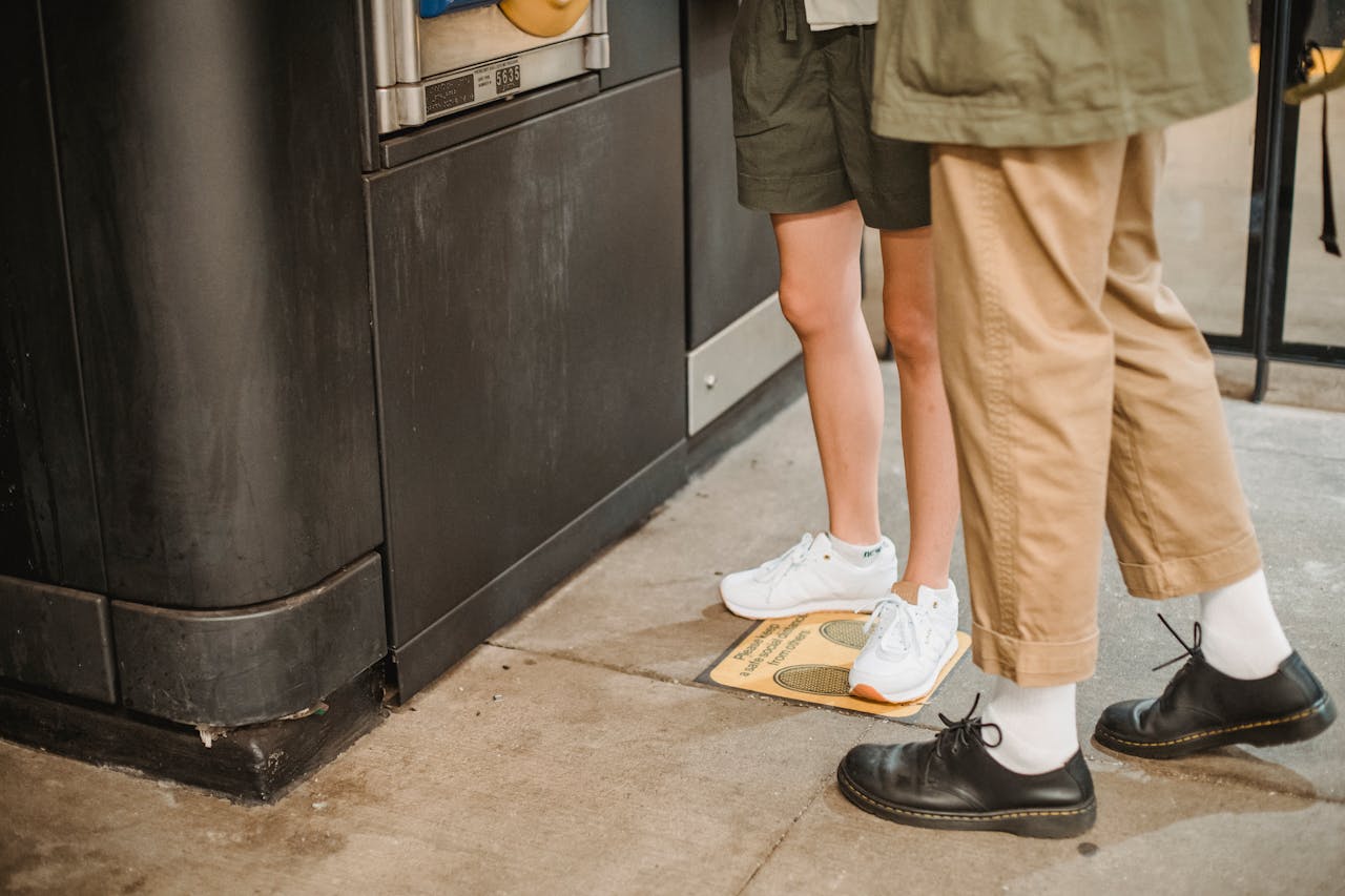 hero-img-02 Casual couple standing by a vending machine in a trendy urban setting, focusing on footwear.