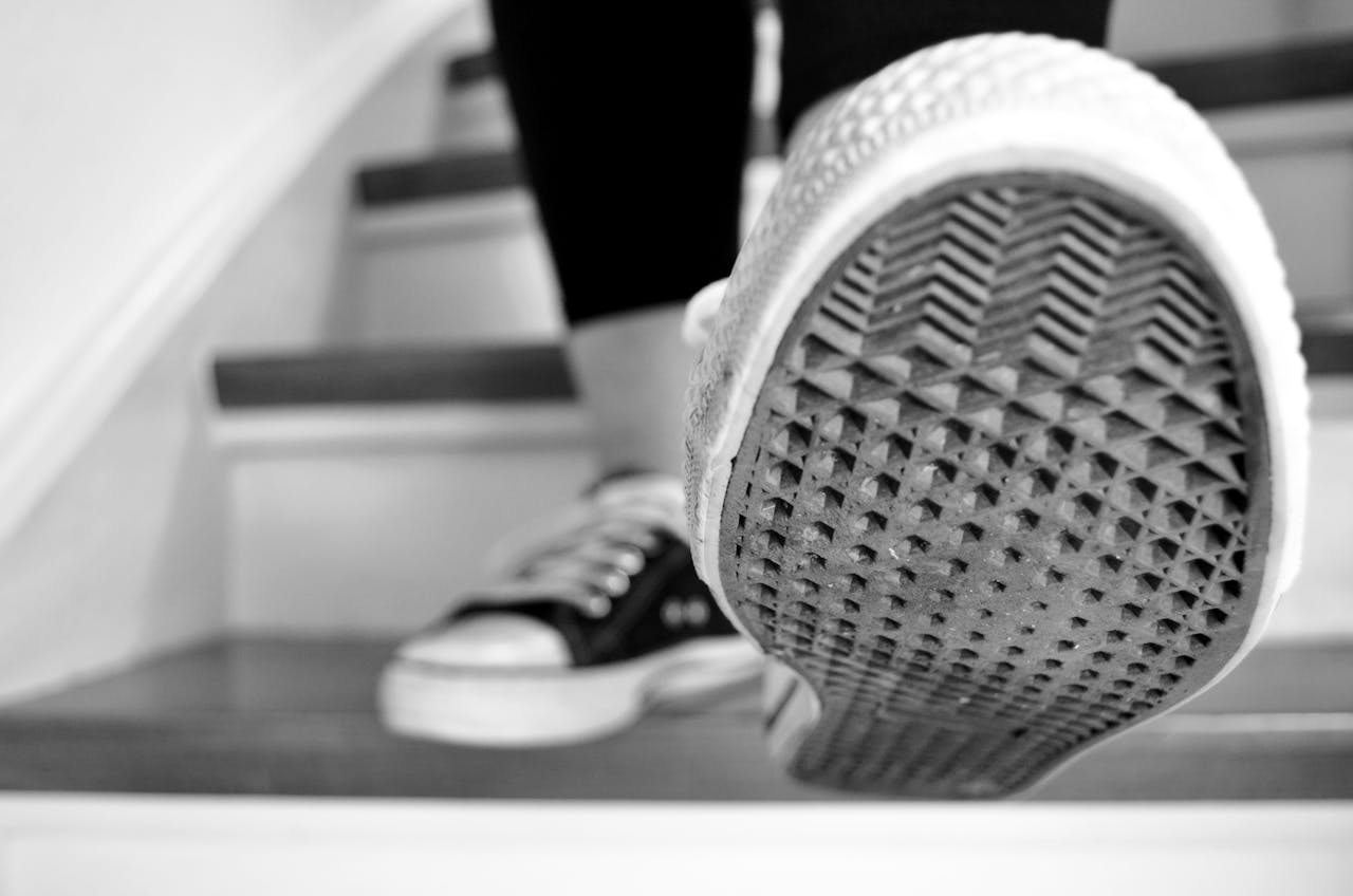 about-01 Black and white shot of sneakers ascending stairs, showcasing the sole pattern.
